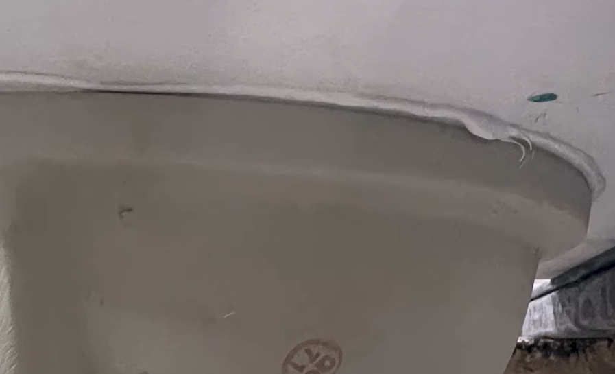 Adhesive bead visible beneath an undermount sink where mechanical clips would not fit