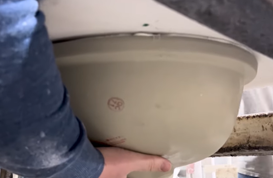Positioning an undermount sink against the countertop deck after applying adhesive
